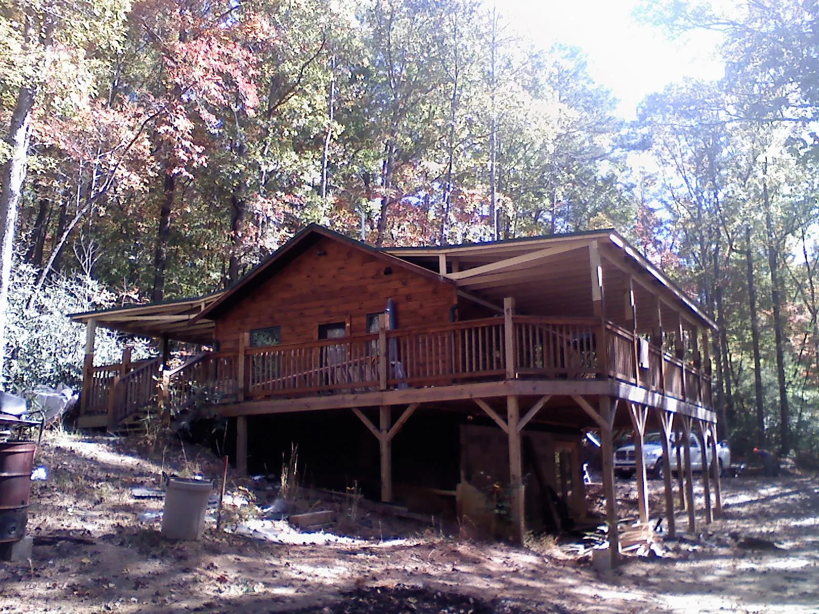 Log cabin with a wraparound porch and metal roof in the fall in Montgomery Village
