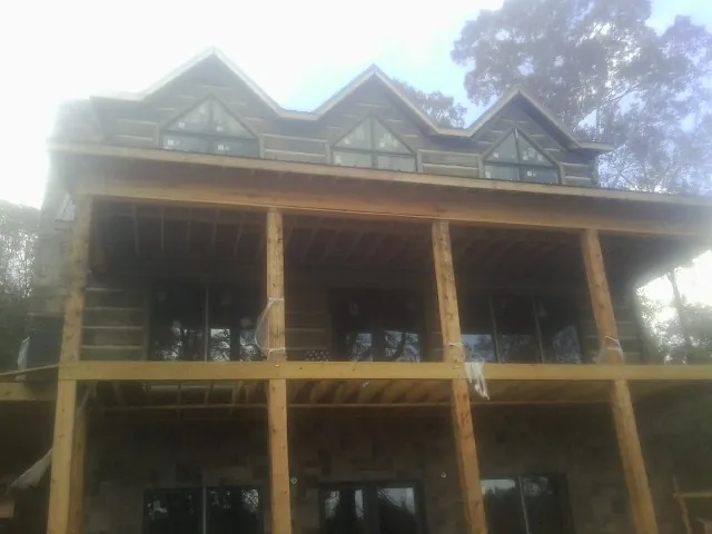 Dormers and porch framing on a large log home under construction — Roof Coating work by our crew in Montgomery Village