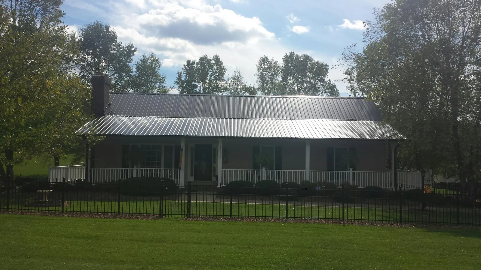 Gray metal roof on a brick ranch with a full width front porch — Gutter Guard Installation work by our crew in Montgomery Village