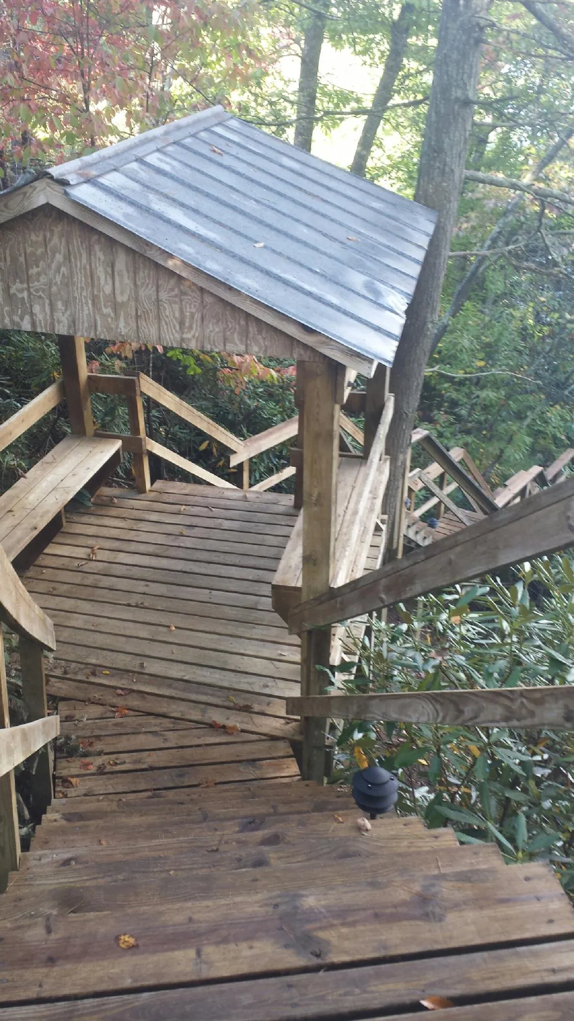 Metal roofed shelter over wooden steps on a wooded walkway — Skylight Repair & Installation work by our crew in Montgomery Village