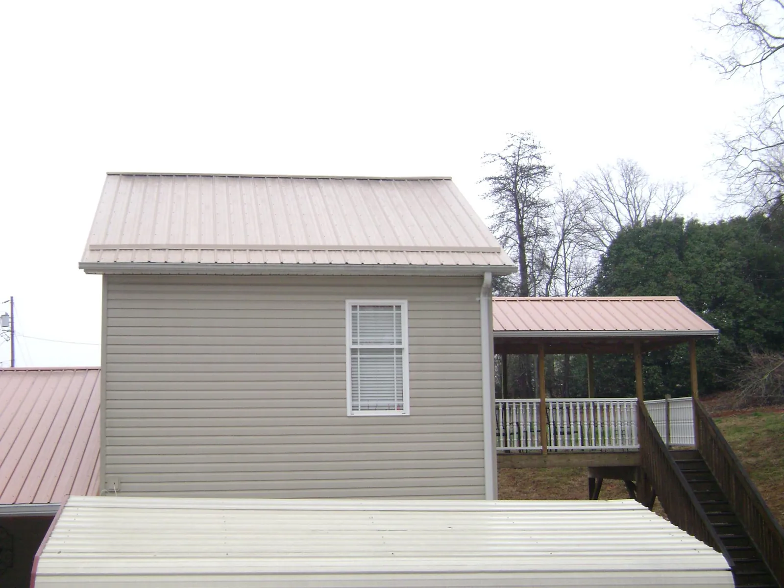 Tan metal roofs on a two story addition and attached porch, from a Roof Replacement job in Montgomery Village