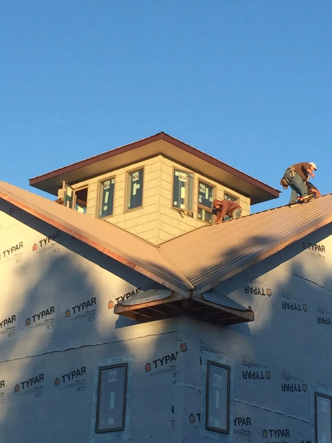 Roofers working around a rooftop cupola on a new metal roof at sunset — Roof Waterproofing in Montgomery Village by Roofing Brothers